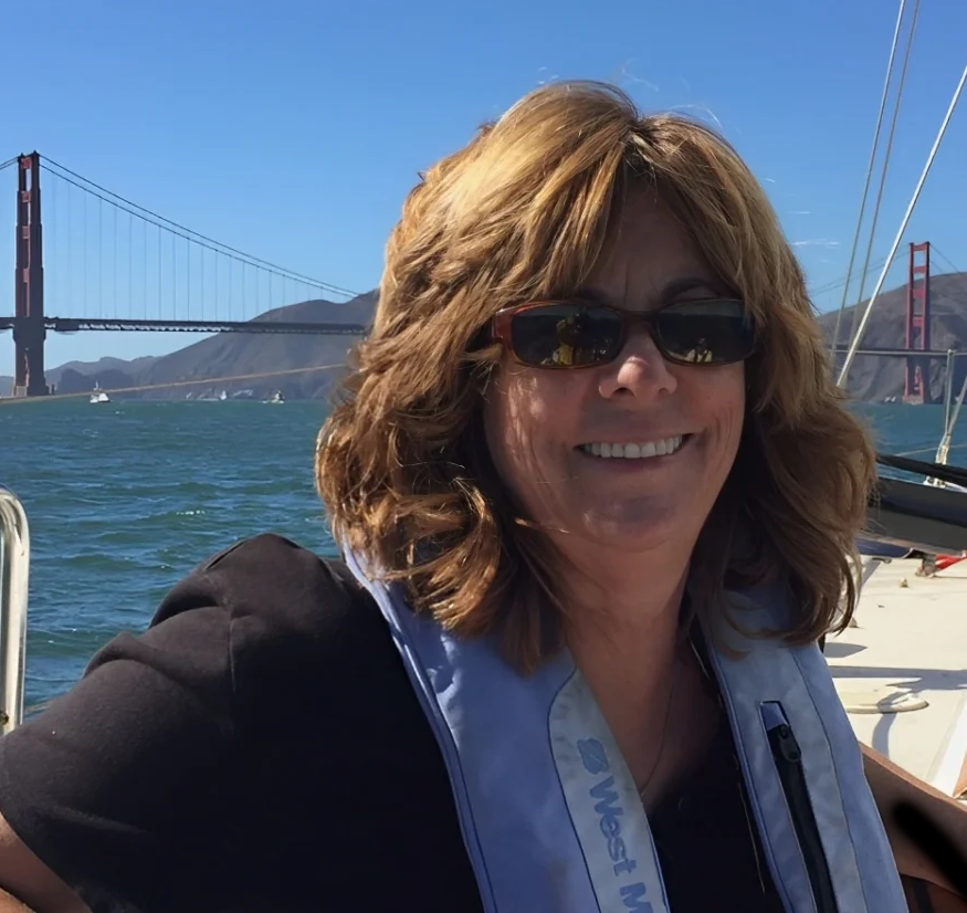 Diana on a sailboat with the Golden Gate Bridge in the background, smiling.