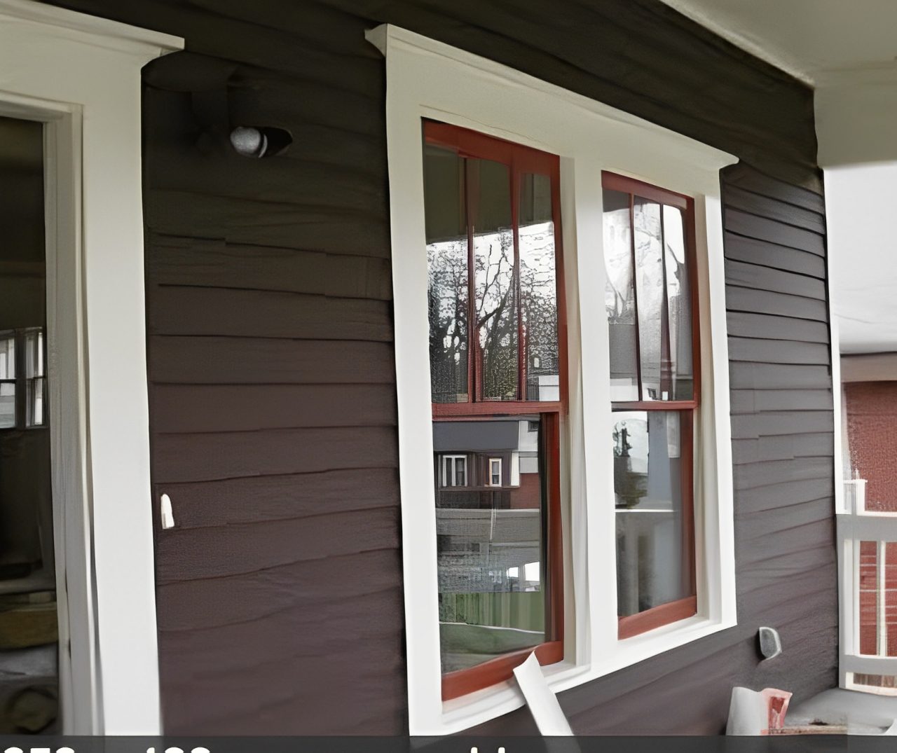 Exterior of a dark brown house with red-framed windows, freshly painted.
