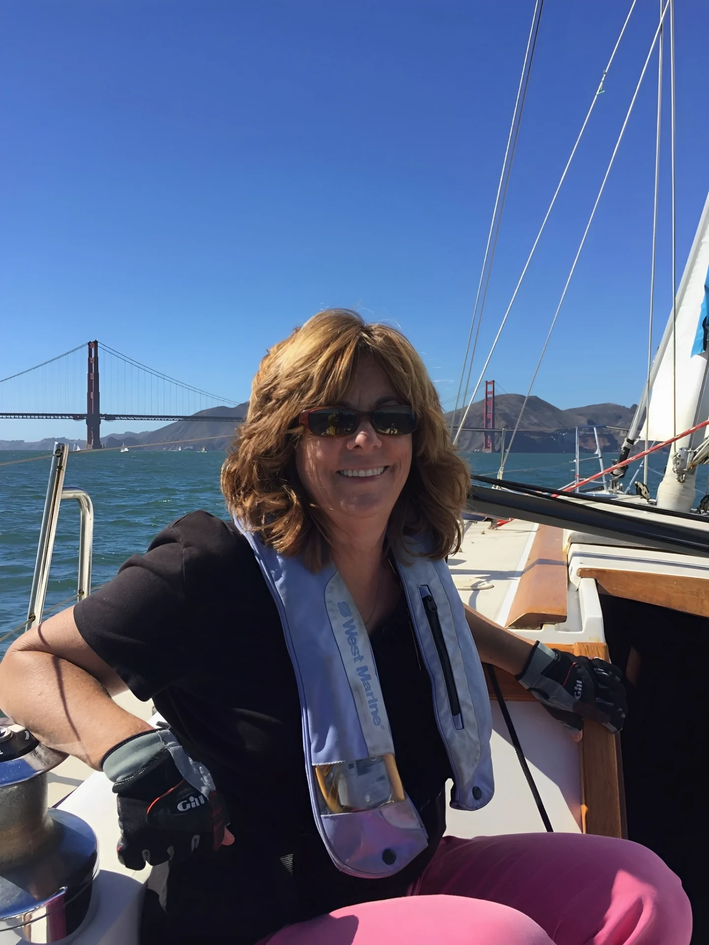 Diana on a sailboat with the Golden Gate Bridge in the background.