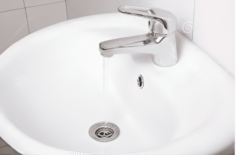 White bathroom sink with running water from a chrome faucet.