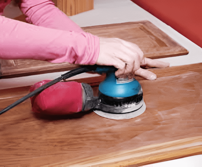 Electric sander smoothing a wooden surface for carpentry work.